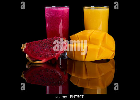 Dragon fruit and mango juices and fruit slices on black reflecting background Stock Photo