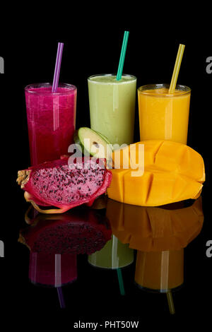Dragon fruit, avocado and mango juices and fruit slices on black reflecting background Stock Photo
