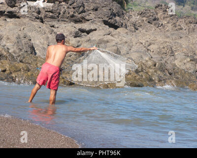 A fisherman throws a fishing net in the river Adyar, Chennai, India ...