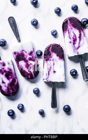 Blueberry coconut milk swirl popsicles with lime on marble background. Stock Photo