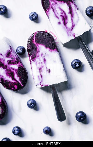Blueberry coconut milk swirl popsicles with lime on marble background. Stock Photo