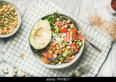 Vegan lunch bowl. Dinner with avocado, mixed grains, beans, sprouts, greens and vegetables over marble table background, top view, horizontal composit Stock Photo