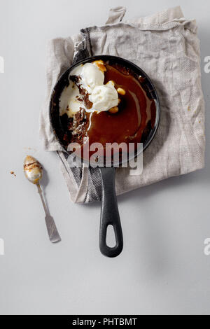 Brownie in a skillet with a scoop of vanilla ice cream, salted caramel and roasted peanuts Stock Photo