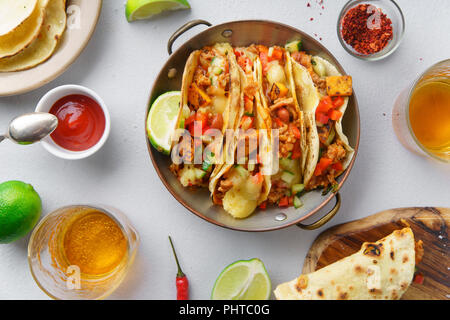Overhead image of mexican tacos with chili con carne and grated cheese served with lemonade, sauces and toppings Stock Photo