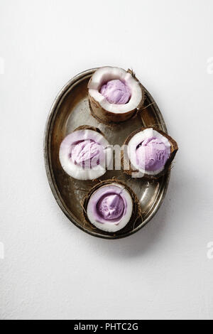 Black currant ice cream served at the halves of cracked coconut arranged on metallic tray Stock Photo