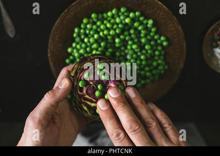 A man prepares lunch with artichokes and peas Stock Photo