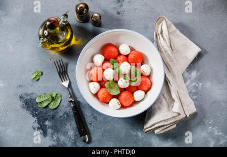 Watermelon salad with mozzarella cheese and mint leaves on gray concrete background Stock Photo