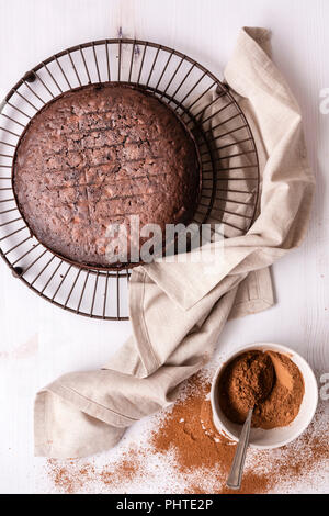 Round home baked chocolate cake cooling on a wire cake rack. Stock Photo