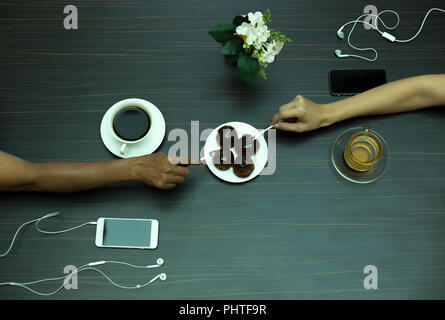 Hand on chocolate Eclair with coffee and tea Stock Photo
