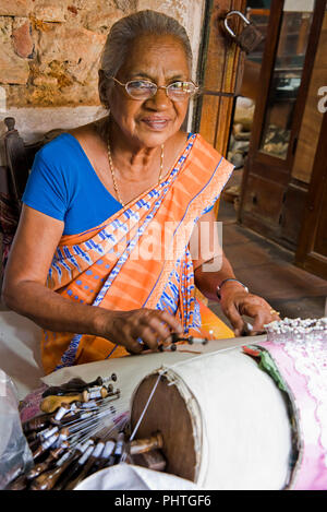 Vertical portrait of an old lady making bobbin lace in Sri lanka. Stock Photo