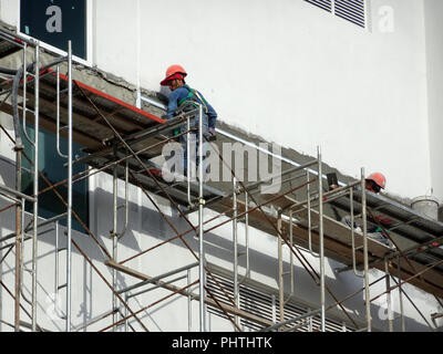 Construction workers plastering wall using cement plaster at the construction site. They are wearing appropriate safety gear to prevent bad happen Stock Photo
