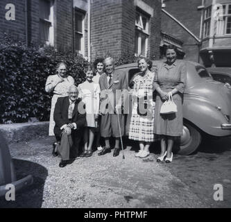 1940s, different generations of a family posing outside by car for family picture. Stock Photo
