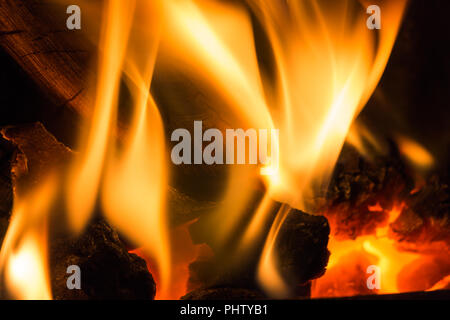 Hot flames from a coal fire with log on left and red glow Stock Photo