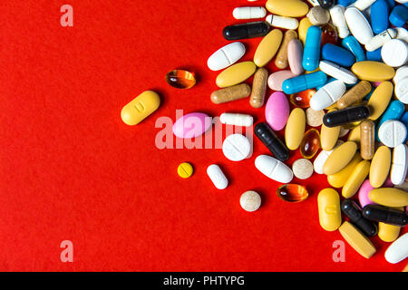 Colourful pills, medication against red background Stock Photo