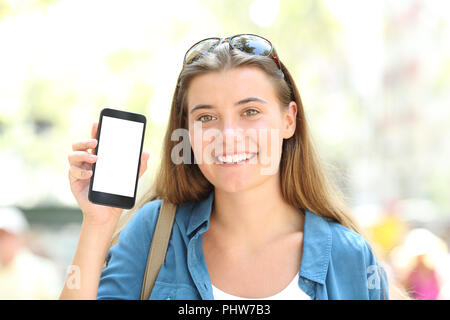 Happy girl showing a blank smart phone screen mockup in the street Stock Photo