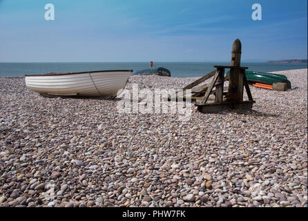 Rowing boats pulled onto Pebble beech at Sidmouth in Devon, with the Devon cliffs in the distance Stock Photo