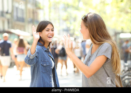 Two happy friends meeting and greeting in the street Stock Photo