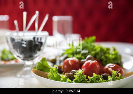 Pickled tomatoes with napa cabbage leaves and other greens on festive table in the restaurant. Catering service in Ukraine restaurant Stock Photo