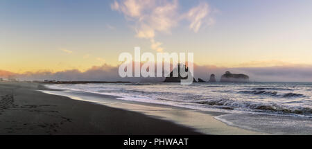 Rialto Beach at dusk with sea stacks covered with clouds coming from the ocean, Olympic National Park, Washington state, USA. Stock Photo