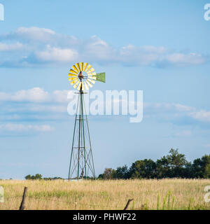 A farm windmill used for livestock water source against blue sky in the Oklahoma farmland, countryside. USA. Stock Photo