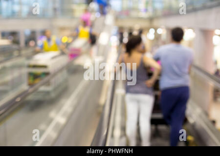 Tourist couple standing on escalator in international airport in motion blur. Stock Photo