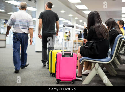 Selested focus on  luggage handle female passenger using her mob Stock Photo