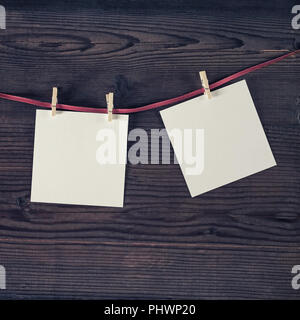 Blank white photo frames hanging with clothespins on vintage wood background. Stock Photo