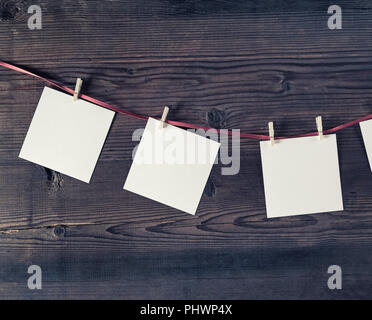 Blank photo frames attach to rope with clothespins on vintage wood background. Stock Photo