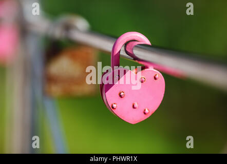 Closed pink heart shaped padlock. Symbol of eternal love. Tradition of lovers on the wedding day. Selective focus. Stock Photo