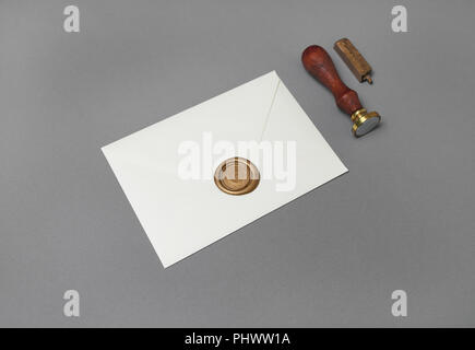Vintage letter envelope with golden wax seal, stamp and spoon on gray paper background. Mock-up for your design. Flat lay. Stock Photo