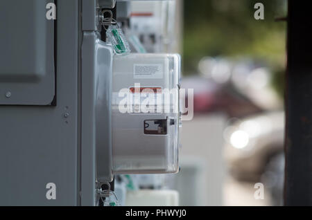 A side view of a meter for measuring electricity usage at an apartment complex in Corpus Christi, Texas USA. Warning labels are clearly visible. Stock Photo