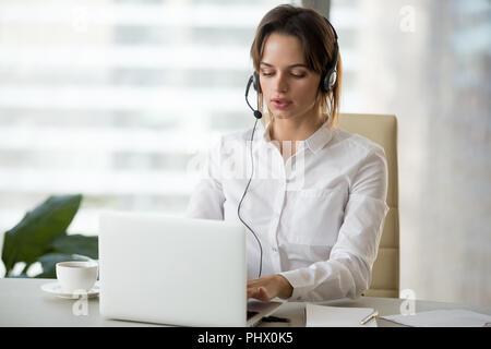 Serious businesswoman with laptop in headset making online confe Stock Photo