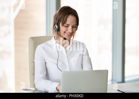 Smiling telemarketer wearing headset consulting customer making  Stock Photo