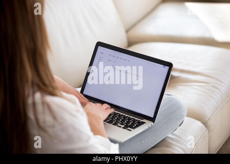 Rear view at woman writing email on laptop at home Stock Photo