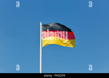 German flag on the flagstaff waving against clear blue sky at sunnt day Stock Photo