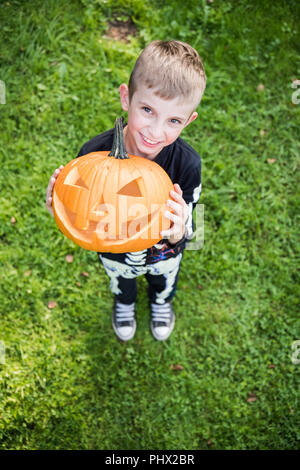 Boy in skeleton costume holding pupmkin at halloween Stock Photo