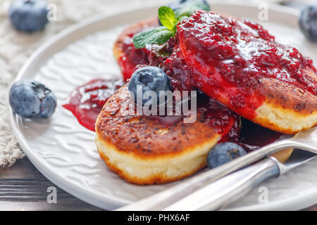Curd pancakes with berry sauce on a plate. Stock Photo