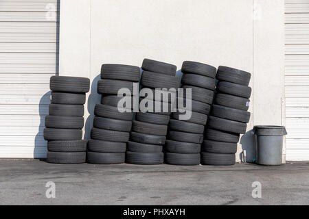 Piles of car tyres against a white wall Stock Photo