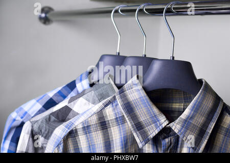 grey blue plaid shirts on hangers Stock Photo
