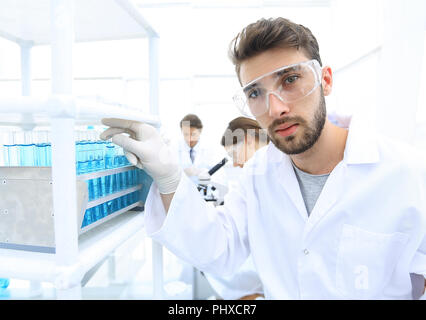 Young male scientist looking at a sample in a test tube side vie Stock Photo