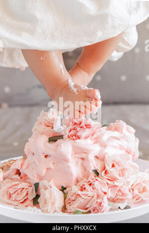 Closeup shot image of  baby girl legs feet stepping in cake during her birthday celebration. Cake-smash first year concept Stock Photo