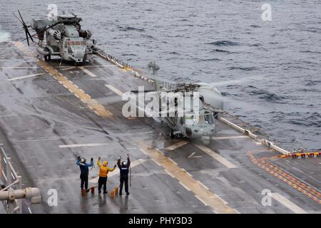 180828-N-JN023-0308 ATLANTIC OCEAN (Aug. 28, 2018) Sailors signal to the crew of a MH-60S Sea Hawk chocks and chains have been removed from the aircraft  during flight operations on the flight deck of the Wasp-class amphibious assault ship USS Kearsarge (LHD 3) as part of the Carrier Strike Group FOUR (CSG 4) Amphibious Ready Group, Marine Expeditionary Unit Exercise (ARGMEUEX). Kearsarge Amphibious Ready Group and 22nd Marine Expeditionary Unit are enhancing joint integration, lethality and collective capabilities of the Navy-Marine Corps team through joint planning and execution of challengi Stock Photo