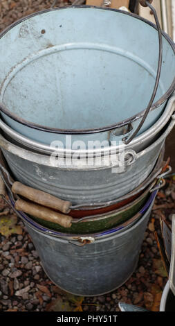 Stack of vintage metal buckets on a market stall, with enamel paint and wooden handles Stock Photo