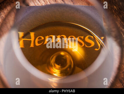 LONDON, UK - SEPTEMBER 04, 2018: Glass of Hennessy Cognac with original coaster on top of wood. Stock Photo