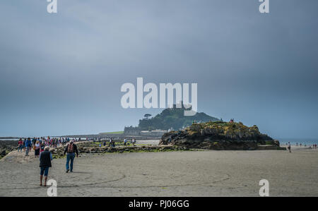 Marazion, England -  May 2018 : People walking on a footpath leading to the St Michaels Mount during low tide, Cornwall, England