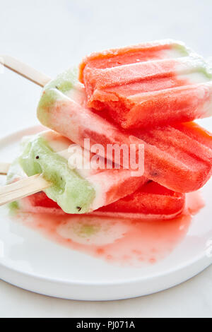 Close-up of a stack of melting homemade berry ice cream in a bowl with spills on a gray marble table. Healthy summer dessert Stock Photo