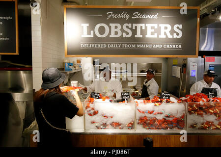 A customer receives a freshly steamed lobster at the Lobster Place inside the Chelsea Market, New York, NY. Stock Photo