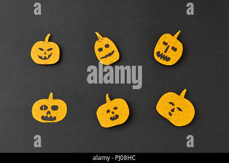 Handcraft decoratide pattern from flying smiling and laughing yellow pumpkins on a black background. Stock Photo