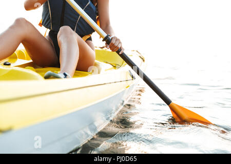 Cropped photo of young woman kayaking on lake sea in boat. Stock Photo