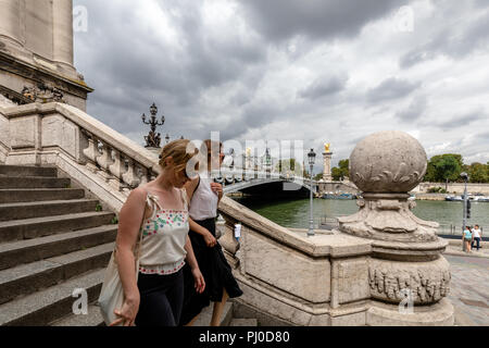 Two young women walking down steps along the river Seine in Paris Stock Photo